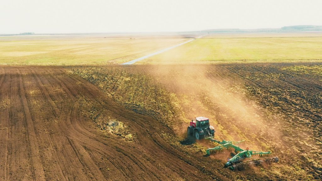 4K Aerial Elevated View.Tractor Plowing Field. Beginning Of Agricultural Spring Season. Cultivator